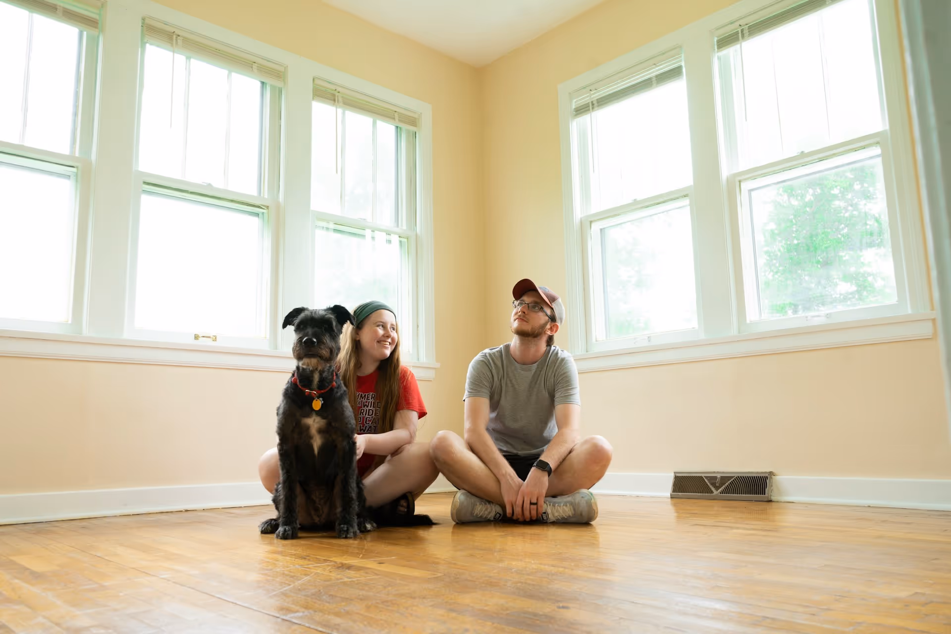 Couple with dog on floor in a new sunlit house