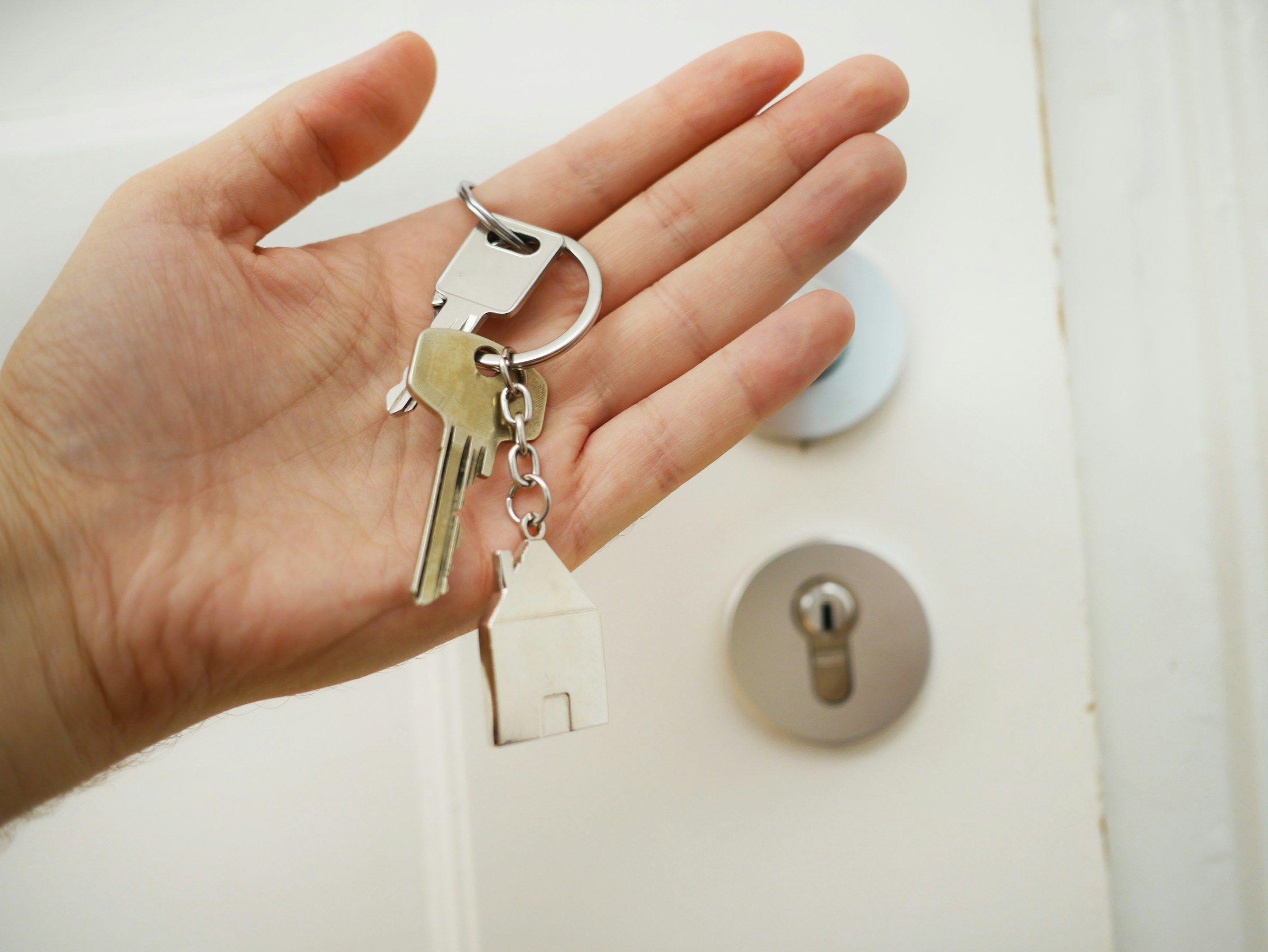 A hand holding a ring of keys in front of a door
