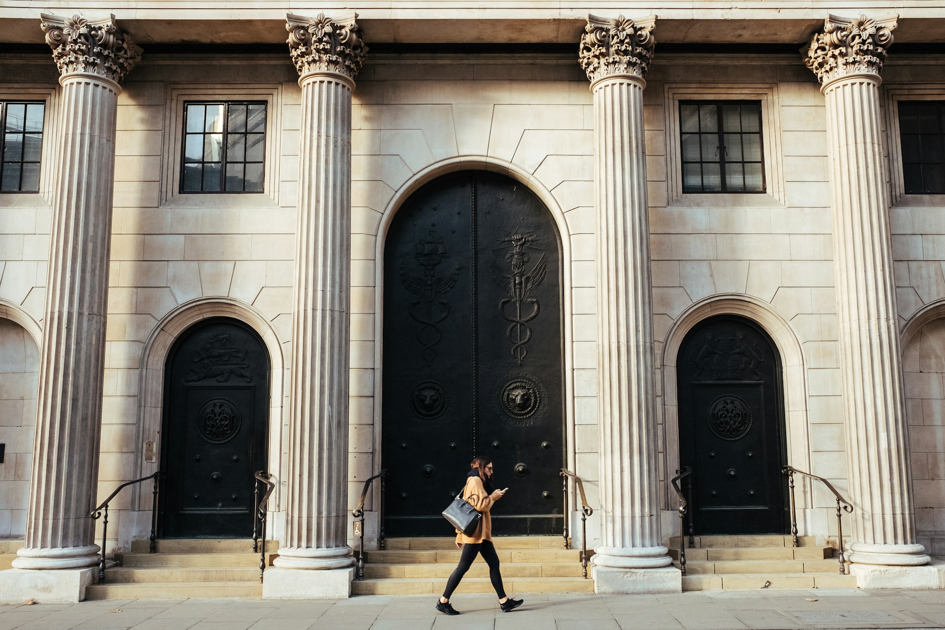man on his phone walking in front of a bank